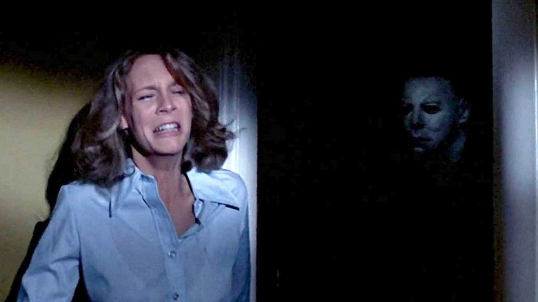 Michael Myers (Nick Castle) stares at a crying Laurie Strode (Jamie Lee Curtis) from a darkened doorway in Halloween (1978)