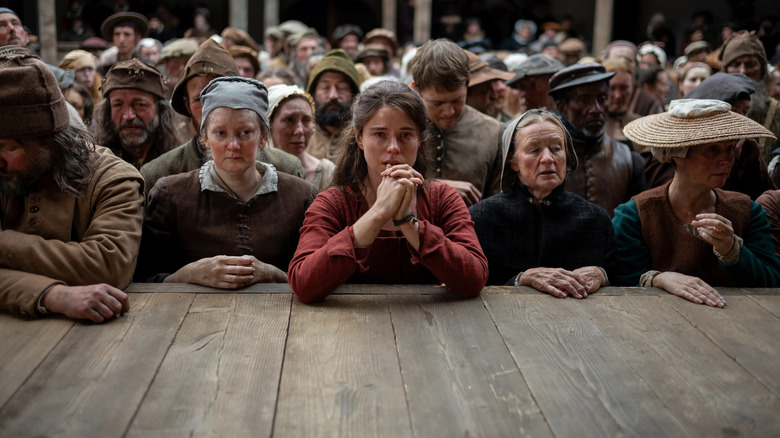Agnes at the front of the stage with the groundlings with her hands clasped in Hamnet