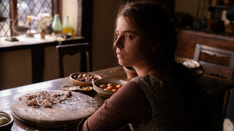 Agnes sits at the table in Hamnet