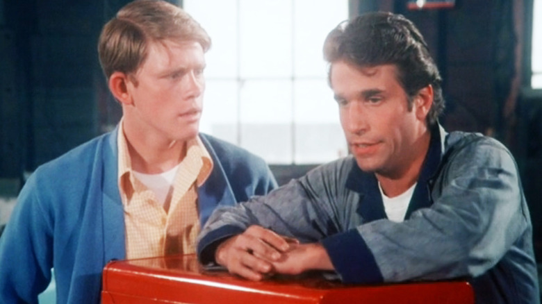 Ron Howard's Richie Cunningham stands beside Henry Winkler's Arthur Fonzarelli in a garage in Happy Days