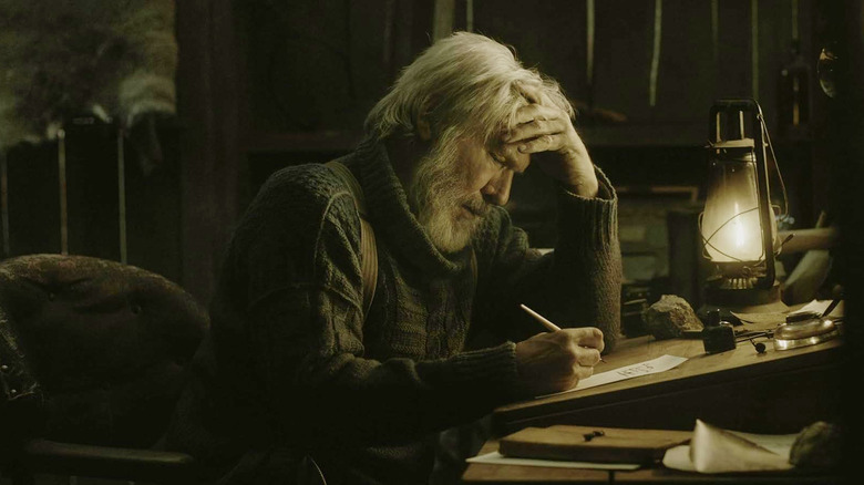 Harrison Ford as John, in distress, writing a letter in The Call of the Wild