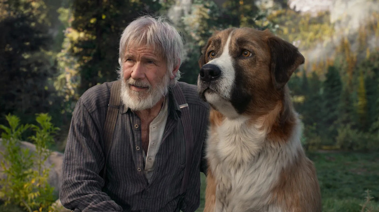Harrison Ford as John and Buck sitting together in the wilderness in The Call of the Wild