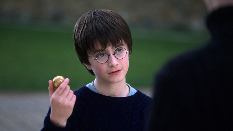 Harry holding a Golden Snitch with extremely blue eyes in Harry Potter and the Sorcerer's Stone