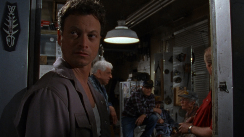 Stu Redman looking behind him while some old guys talk in the background in The Stand (1994)