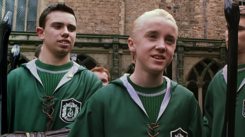 Draco Malfoy standing in front of the rest of the Slytherin quidditch team in Harry Potter and the Chamber of Secrets