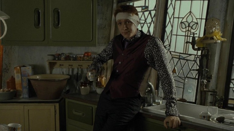 A bandaged George Weasley (Oliver Phelps) drinks coffee in a kitchen in Harry Potter and the Deathly Hollows: Part 1