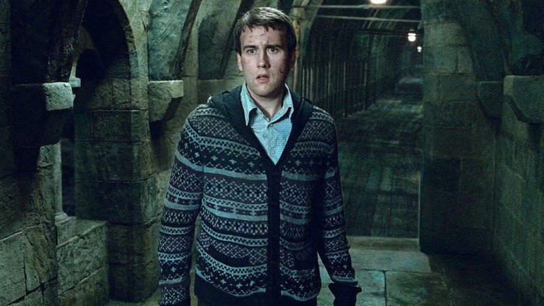 Matthew Lewis as Neville Longbottom in Harry Potter and the Deathly Hallows: Part 2, standing in front of a covered bridge and looking off at something with concern.