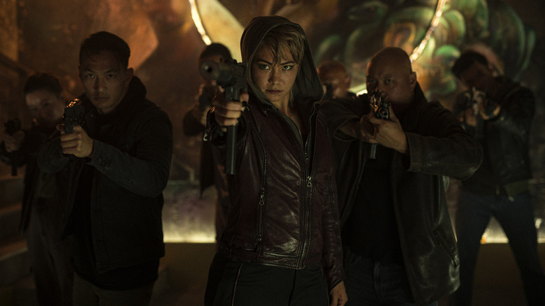 A gang armed with weapons enter a club and raise them at someone off screen in Havoc