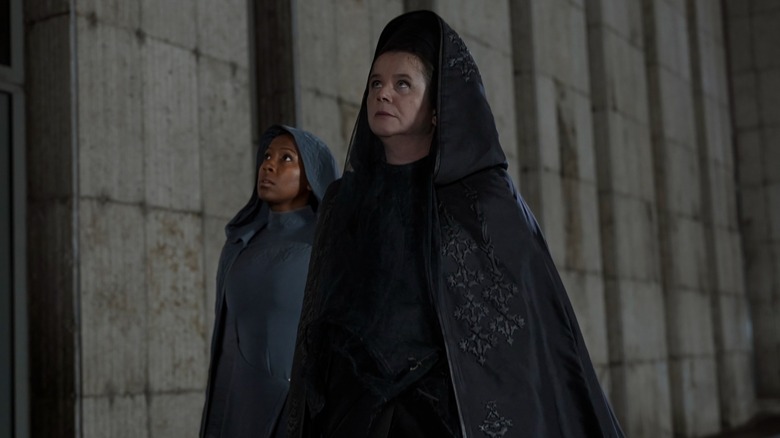 Jade Anouka's Sister Theodosia and Emily Watson's Valya Harkonnen, both wearing cloaks, look upwards offscreen in Duce: Prophecy
