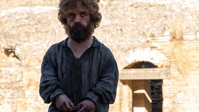 Peter Dinklage's Tyrion Lannister, dirt-covered and looking serious, stares at a character offscreen in Game of Thrones