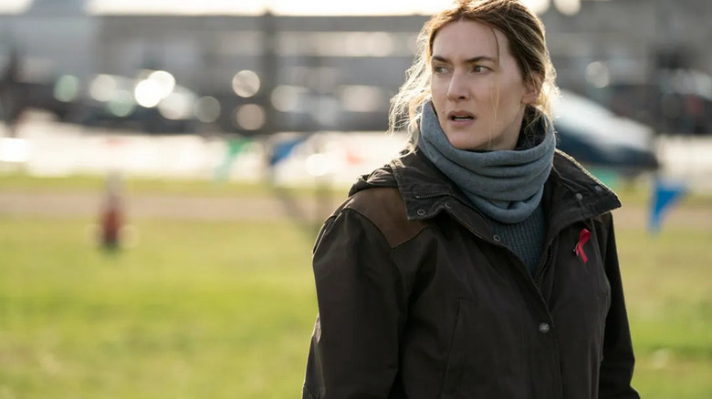 Kate Winslet wearing coat and scarf as Mare in Mare of Easttown