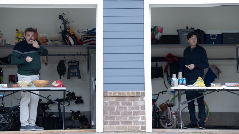 David Harbour as Floyd standing in a garage next to Jason Bateman as Clark in DTF St. Louis