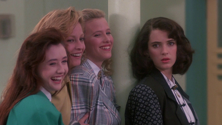 Winona Ryder as Veronica looks dismayed as the titular Heathers laugh at a nasty prank