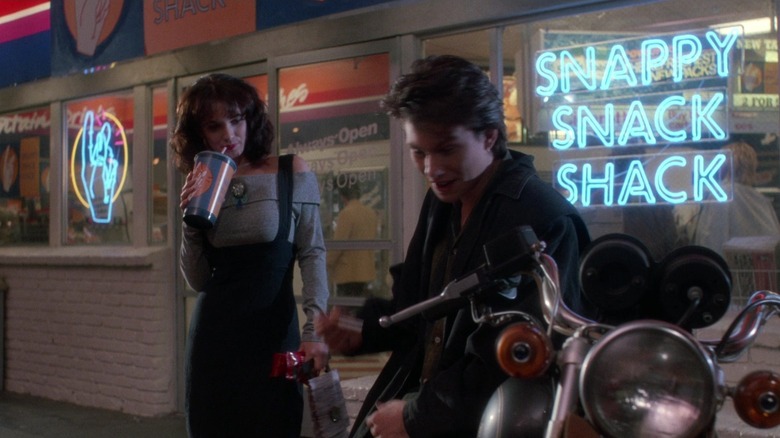 Winona Ryder as Veronica drinks a Slurpee while Christian Slater as J.D. leans on his motorcycle in Heathers