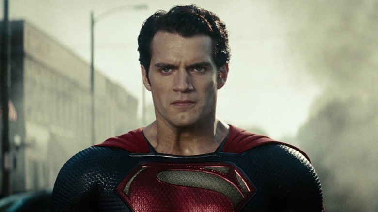 Henry Cavill's Superman stands looking upset in a street filled with smoke in Man of Steel