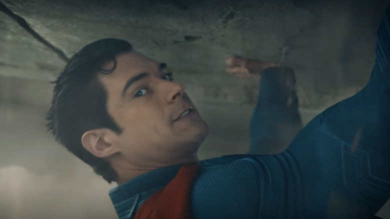 David Corenswet's Superman looks to the right as he holds up a giant slab of concrete in Superman