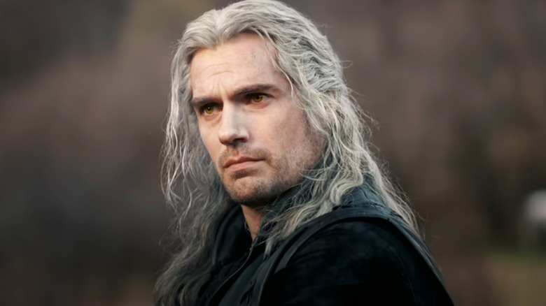 Henry Cavill's Geralt of Rivia stands against a blurry background in The Witcher