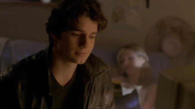 Henry Cavill's Mike smiling and looking downward, and a woman out of focus in the background, in Hellraiser: Hellworld