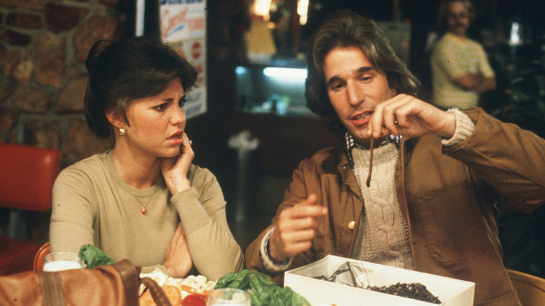 In the middle of a restaurant, Jack (Henry Winkler) holds up a worm, prompting a confused and concerned look from Carol (Sally Field) in a scene from the film Heroes