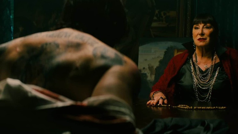 John Wick with his back exposed in front of The Director