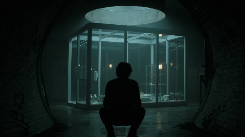 Joe in the darkness looking at his cage in You