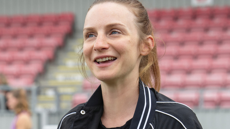 Lizzie Davis standing on the pitch, smiling, in Ted Lasso Season 4