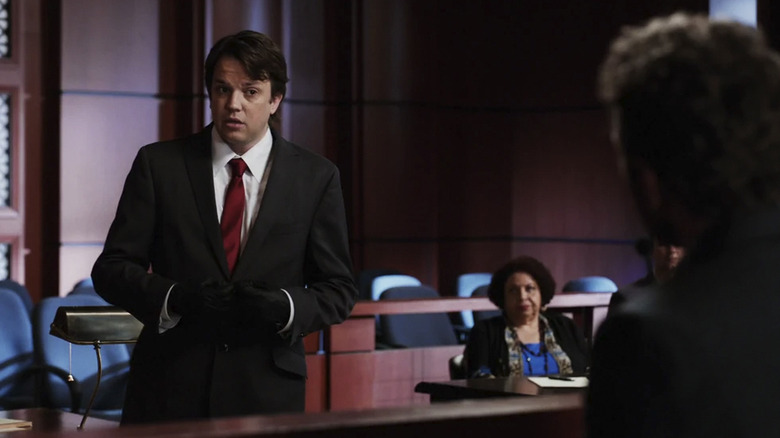Zack Addy wearing a suit in a courtroom, looking at a witness in Bones