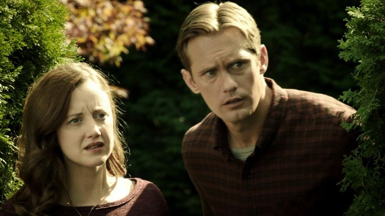 Claire (Andrea Riseborough) and Ray (Alexander Skarsgård) look towards their right with concerned expressions in Hidden