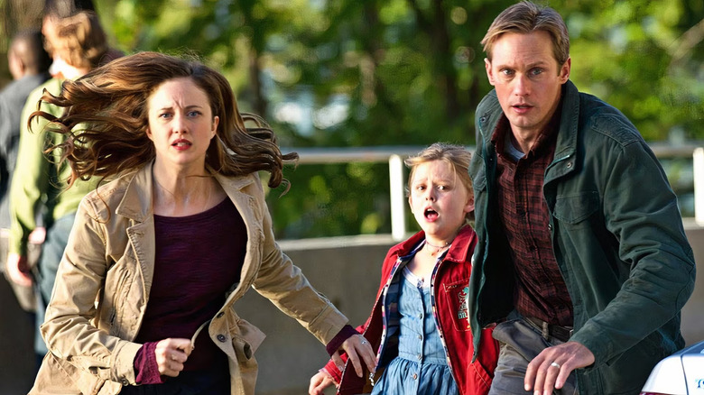 Ray (Alexander Skarsgård), Claire (Andrea Riseborough), and Zoe (Emily Alyn Lind) run with worried expressions on their faces in Hidden