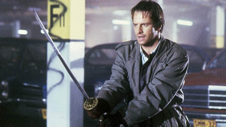 Christopher Lambert as Connor MacLeod in a parking garage with a sword in Highlander