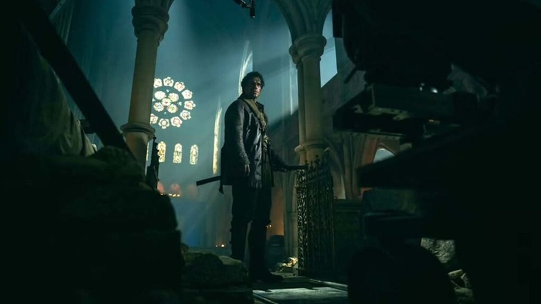 Henry Cavill as MacLeod brandishes a katana in a church in Highlander