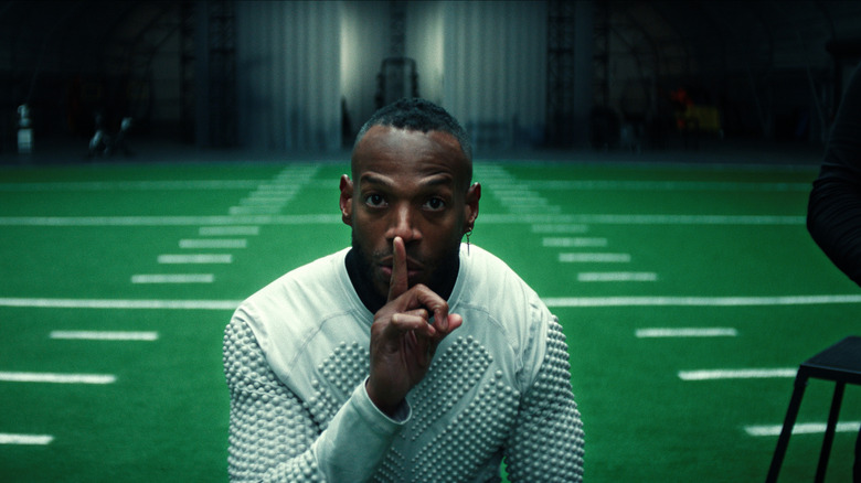 Marlon Wayans as Isaiah White holding up his fingers in a shushing motion while on a practice football field in Him