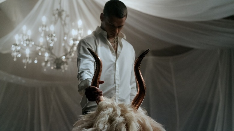 Cameron Cade holding the horn of a goat-head costume piece in Him