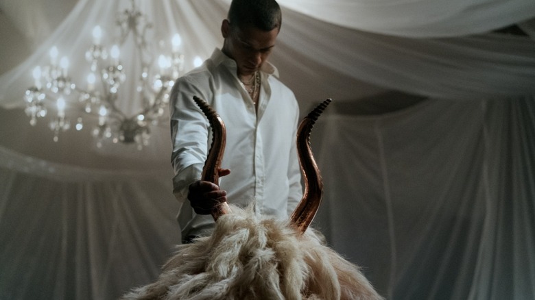 Cam Cade grabs a bizarre mascot head of a goat by the horn in HIM