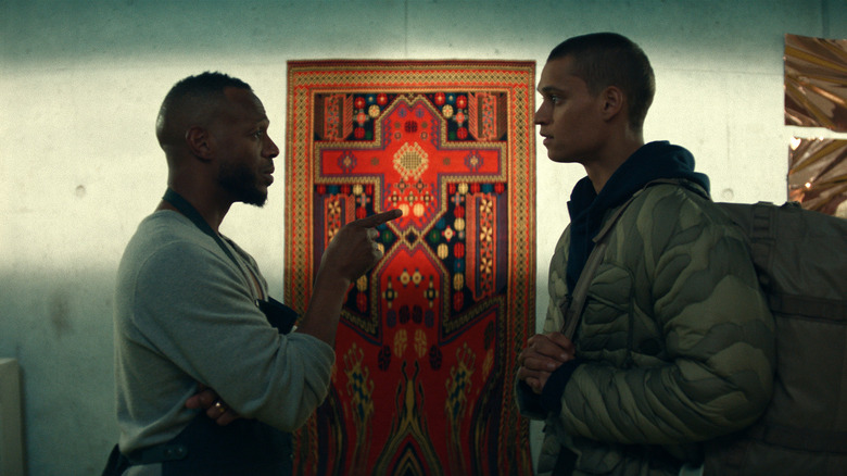 Isaiah and CAm talk in front of an ornate door in HIM