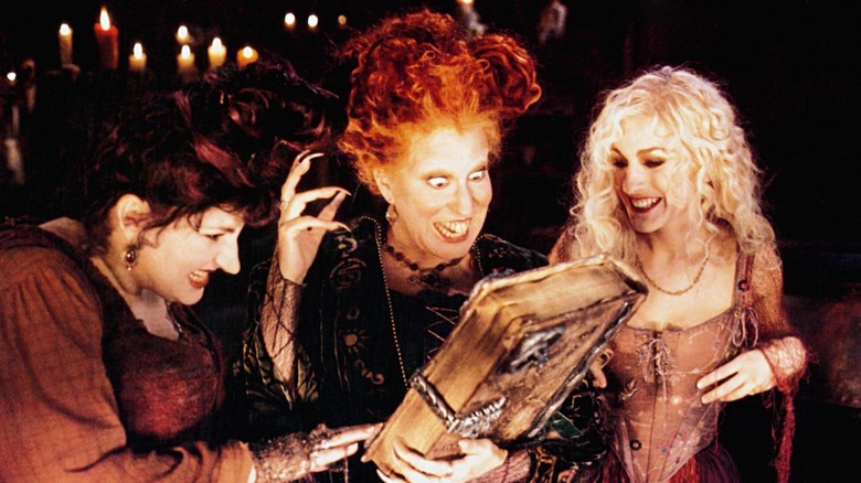 Kathy Najimy, Bette Midler, and Sarah Jessica Parker looking at their book of spells in Hocus Pocus