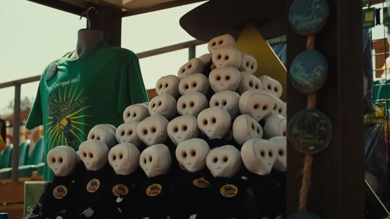 a pyramid stack of alien dolls next to a bust with a green t-shirt and button on