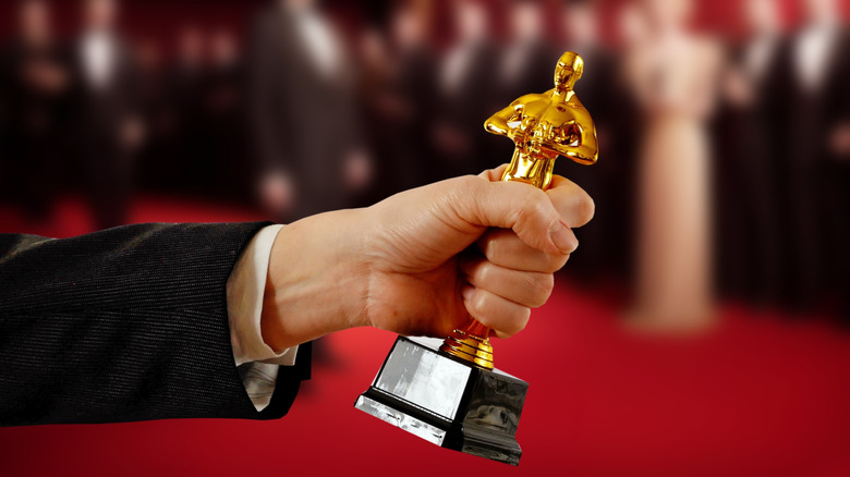 a hand holding an Oscar statue