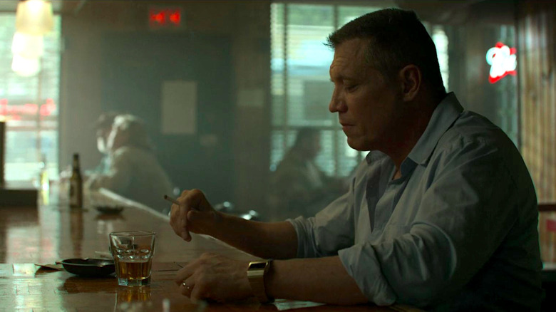 Bill Tench sits at a bar and smokes in "Mindhunter"