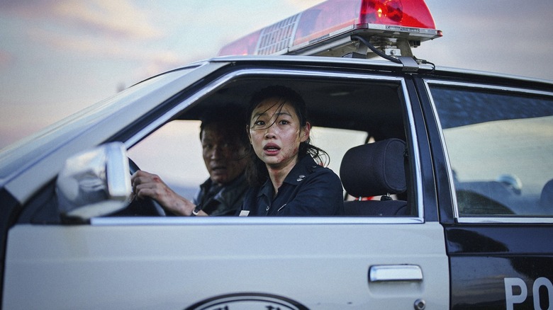 Hoyeon as Sung-ae driving a police car next to Hwang Jung-min as Bum-seok in Hope