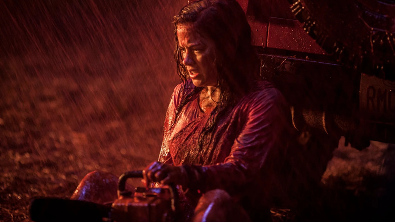 Evil Dead Mia sits with a chainsaw