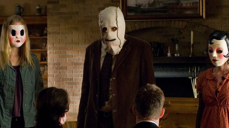 Two women and a man in masks stand in a line