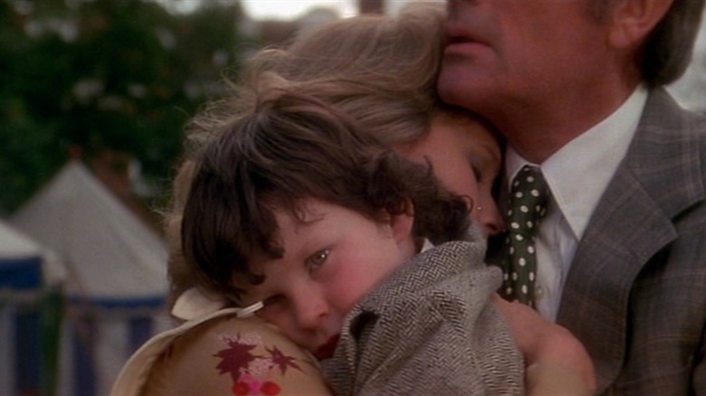 Gregory Peck and Lee Remick as Robert and Katherine Thorn in The Omen, clutching Damien (Harvey Stephens) as they embrace