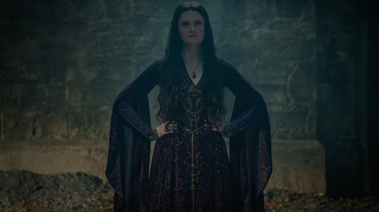 Gayle Rankin as Alys Rivers standing in front of a stone wall with her hands on her hips in House of the Dragon