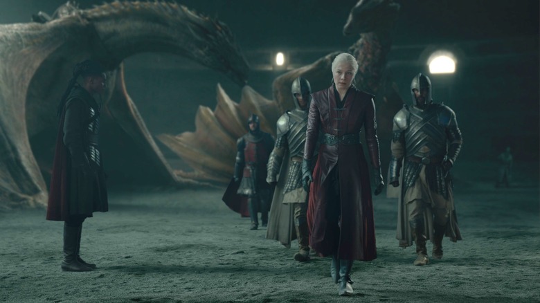 Emma D'Arcy as Rhaenyra Targaryen walking away from her dragon and surrounded by guards in House of the Dragon