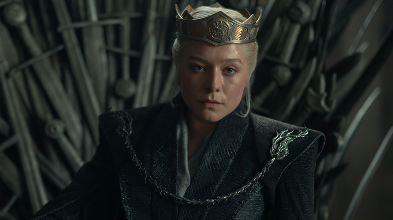 Emma D'Arcy as Rhaenyra Targaryen wearing her crown and sitting on a throne made of swords in House of the Dragon