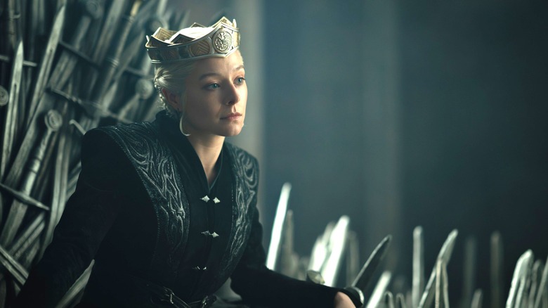 Emma D'Arcy as Rhaenyra Targaryen wearing a crown and sitting on a throne made of swords in House of the Dragon