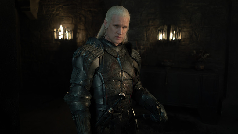 Matt Smith as Daemon Targaryen wearing full armor and standing in a darkened room in House of the Dragon
