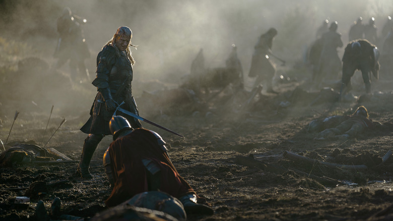 Matt Smith as Daemon Targaryen in full armor and wielding a sword in a battle with several soldiers in the background in House of the Dragon