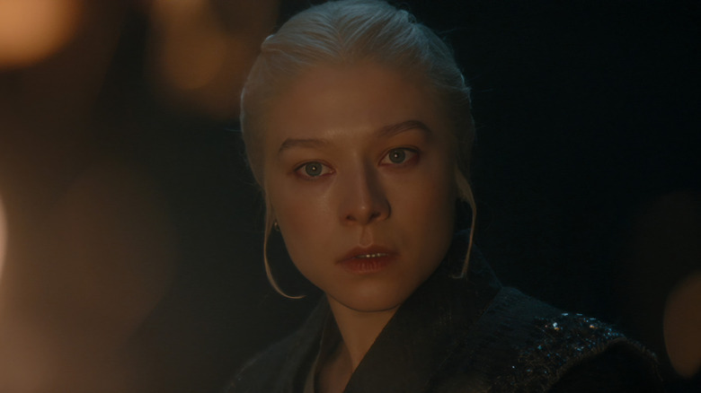 Emma D'Arcy as Rhaenyra lit by firelight and looking concerned in House of the Dragon